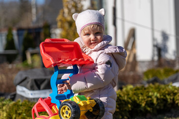 Toddler's Joy: A young child playing with colorful toy excavator outside on a sunny day, evoking...