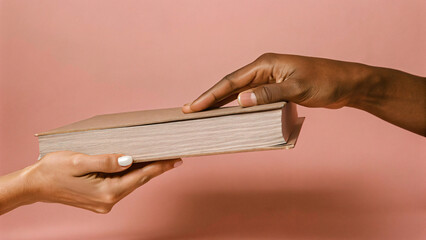 Exchange of a book between two hands against a soft pink background