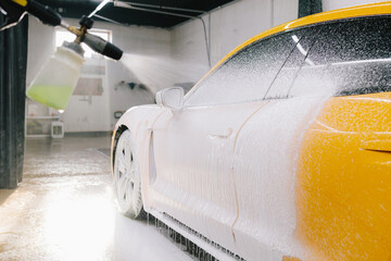 Second phase of detailing washing in car service. Process of spraying foam on the car body in the...