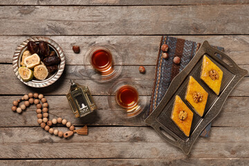 Glasses of tasty Turkish tea with baklava, fanoos and tasbih on wooden background. Ramadan...