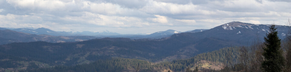 Fototapeta premium Breathtaking Mountain Panorama with Moody Clouds and Vibrant Greenery
