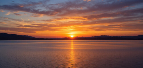 A panoramic view of a serene lake at sunset, with a colorful sky reflecting on the calm water.