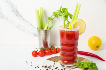 Glass of bloody mary cocktail and ingredients on white background