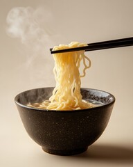 Steaming hot bowl of noodles lifted by chopsticks in a minimalist clean presentation