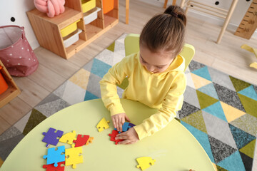 Cute little girl doing puzzle at home, top view