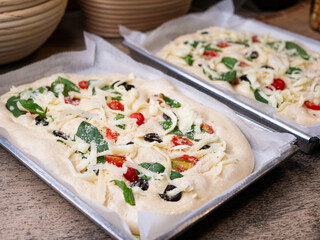 Raw Focaccia with olive tomatoes and rosemary. Homemade Italian Sourdough Bread on white cafe table.