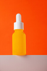 Plastic yellow tube for cream or lotion. Skin care or sunscreen cosmetic with stylish props on orange background.