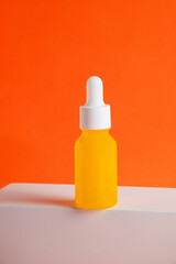 Plastic yellow tube for cream or lotion. Skin care or sunscreen cosmetic with stylish props on orange background.