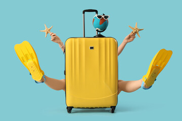 Female tourist in flippers with starfishes and suitcase on blue background © Pixel-Shot