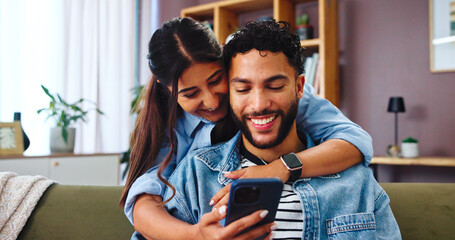 Couple, smartphone and happy on sofa with hug, social media and funny gossip story in home. Woman,...
