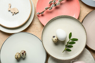 Different clean plates with Easter eggs, fresh leaves and pussy willow branches on beige background