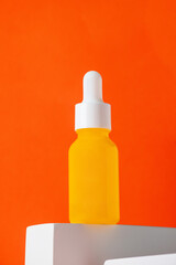 Plastic yellow tube for cream or lotion. Skin care or sunscreen cosmetic with stylish props on orange background.
