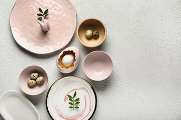Different clean plates with Easter eggs, toy bunny and fresh green leaves on white background