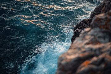 Obraz premium Ocean Waves Crashing Against Rocky Shoreline at Sunset with Dramatic Lighting