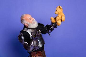 Armored man holding teddy bear humorously evokes medieval and modern contrasts