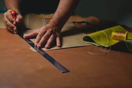 Shoemaker cutting leather with precision and steel ruler