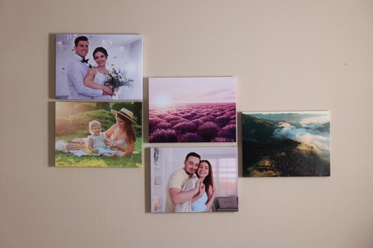 Canvas with different printed photos on beige wall indoors
