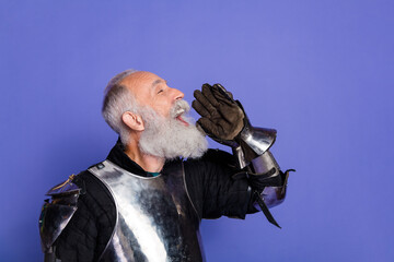 Elderly man in medieval knight armor shouting enthusiastically against a purple backdrop
