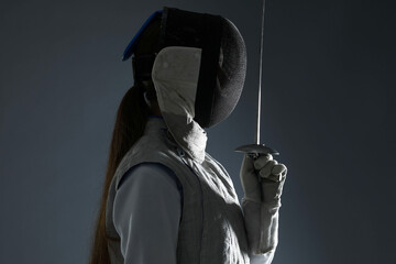 Fencer with epee on gray background. Combat sport
