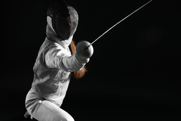 Fencer with epee practicing on black background