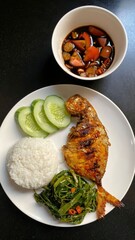 Grilled fish and other dishes arranged on a white plate