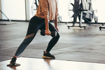 Athletic woman exercising with dumbbell during workout in gym