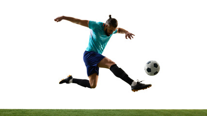 Dynamic photo of young athletic football player leaping in motion and scoring goal against white background on grassy playground. Concept of professional sport, championship, match, victory.