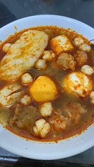 A bowl of various food items in spicy red broth