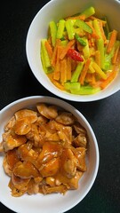 Two bowls of cooked food displaying chicken and vegetable options