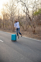 Happy Indian solo traveler with her stroller or bag waiting roadside
