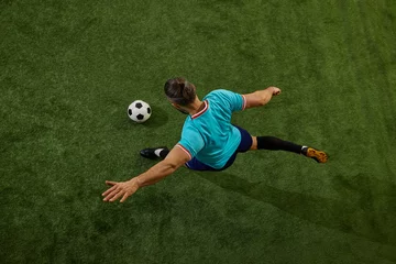 Fotobehang Top-down perspective of skilled football player executing powerful pass, leg fully extended, ball rolling on stadium grass. Concept of game control, strategy, professional sport, match, playmaking. © Lustre Art Group 