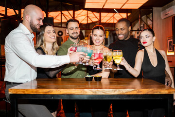 A group of young people of different ethnicities between 20 and 30 years old have fun in a nightclub.Friends are toasting with glasses of alcohol while smiling.Party friends concept.