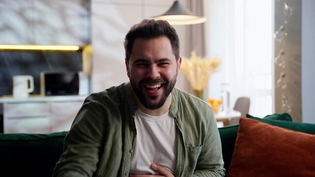 Laughing smiling happy Caucasian man male guy homeowner businessman joking funny pointing index finger you joy humor fun laugh joke looking at camera gesture laughter sitting sofa indoors living room