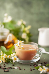 Composition with cup of jasmine milk tea and flowers on green background