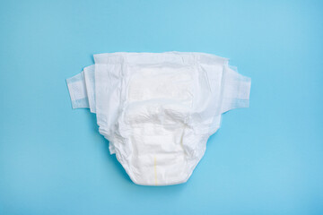 Diaper on light blue table background. Top view.