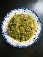 Green chili sauce covered cooked food served on decorated ceramic plate