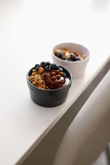 Dessert bowls with granola, Greek yogurt, blueberries, propolis and honey stand on a white table