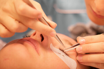 Eyelash extension service in a bright beauty salon during afternoon hours with a professional beautician at work