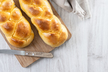 Traditional Easter braided bread. Tsoureki braid on white wooden table. Top view. Copy space