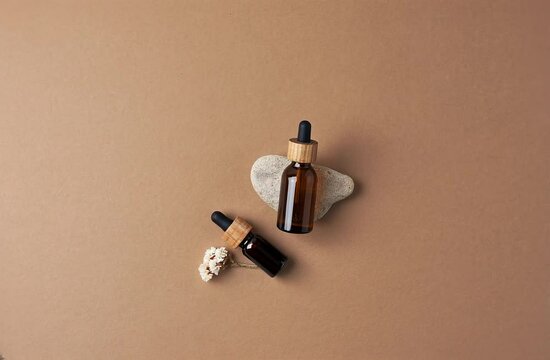 Skin care products on brown background with flowers, stone. Rotating background. Flat lay, copy space.