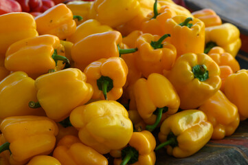 Vibrant display of yellow bell peppers at a bustling local market during the sunny afternoon