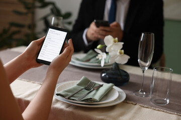 Couple choosing dishes from digital menu at restaurant, closeup