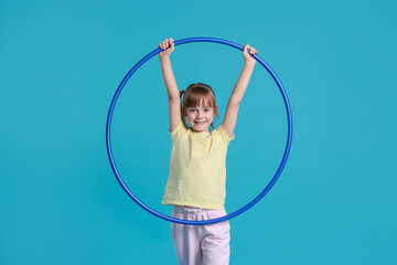 Cute little girl with hula hoop on light blue background © New Africa