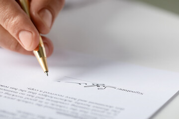 Man putting signature on document at table, closeup. Space for text