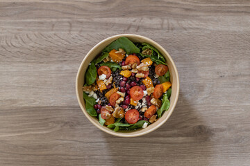 Fresh salad with lentils, pomegranate, walnuts, feta cheese, and cherry tomatoes, served in an eco-friendly bowl. A colorful and healthy option for a restaurant menu or take-away