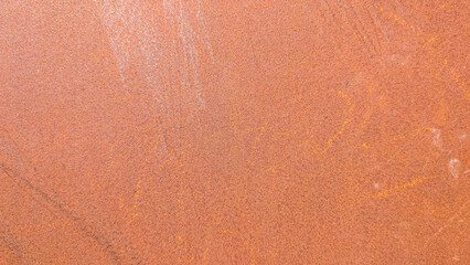 Rusty metal surface revealing extensive corrosion, showcasing weathered texture in rich orange...