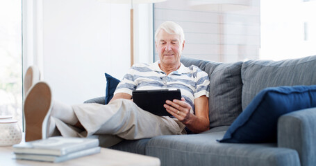 Obraz premium Couch, senior man and relax with tablet for online game, web surfing and reading ebook at home. House, elderly person and chill on sofa with digital poker, social media and connection in retirement