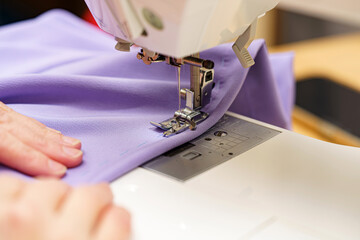 A woman seamstress cuts out pieces for sewing from fabric and sews them on a sewing machine. Sewing...