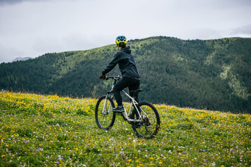 Naklejka premium Woman cyclist riding mountain bike on beautiful forest mountain top