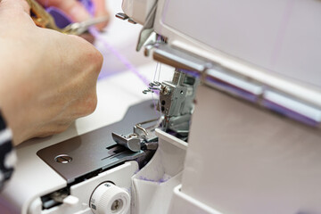 A woman seamstress cuts out pieces for sewing from fabric and cuts the fabric with scissors. Sewing industry of the textile industry.